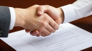 manos estrechandose sobre contrato legal
