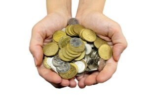 manos sosteniendo monedas y billetes variados