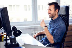 Cuáles son las mejores frases para un nuevo trabajo y motivarte 33 persona sonriente mirando su escritorio nuevo